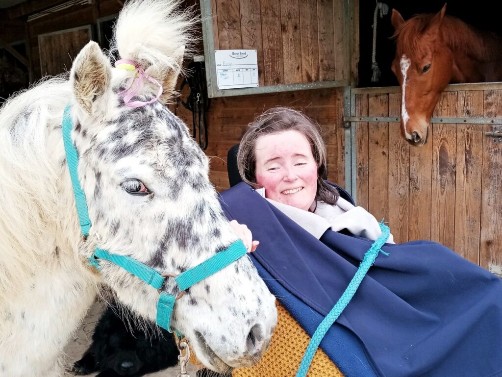 Une personne en situation de handicap entourée de chevaux